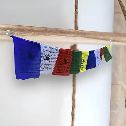 A hand block printed tibetan prayer flag strand in blue white red green yellow and purple with intricate black script and symbols