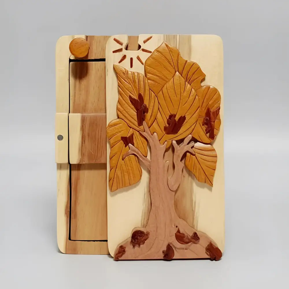 Hand carved wooden tree box with golden brown leaves and dark accents on light wood featuring hidden compartment