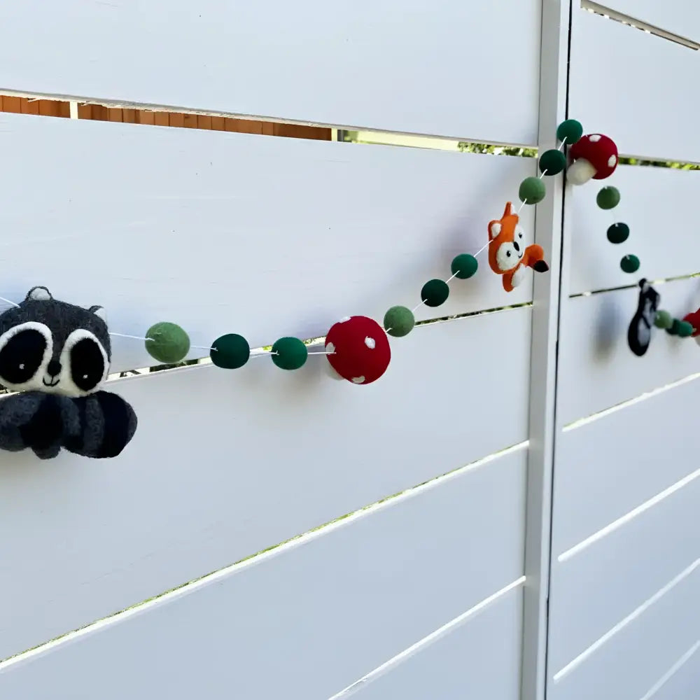 Hand-felted wool garland with whimsical forest friends and colorful pom-poms in red green and black