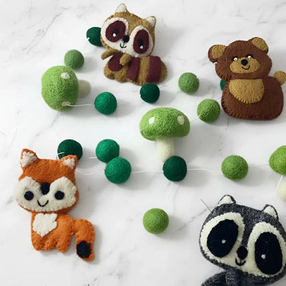 Hand-felted wool garland of whimsical forest friends with embroidered raccoons, bears, and foxes in soft brown, orange, and gray tones