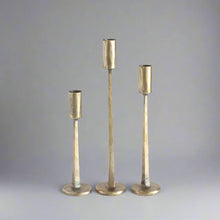 Three hammered brass candlesticks on hand forged iron candle stands in gold and black