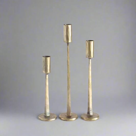 Three hammered brass candlesticks on hand forged iron candle stands in gold and black