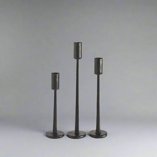 Set of three dark hand forged iron candle stands with round bases for a stylish look