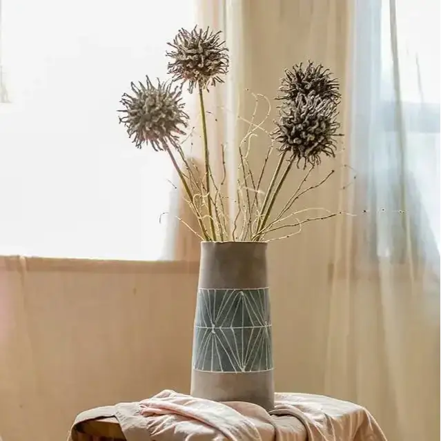 Hand-painted terracotta table pitcher vase with geometric pattern holding dried floral stems