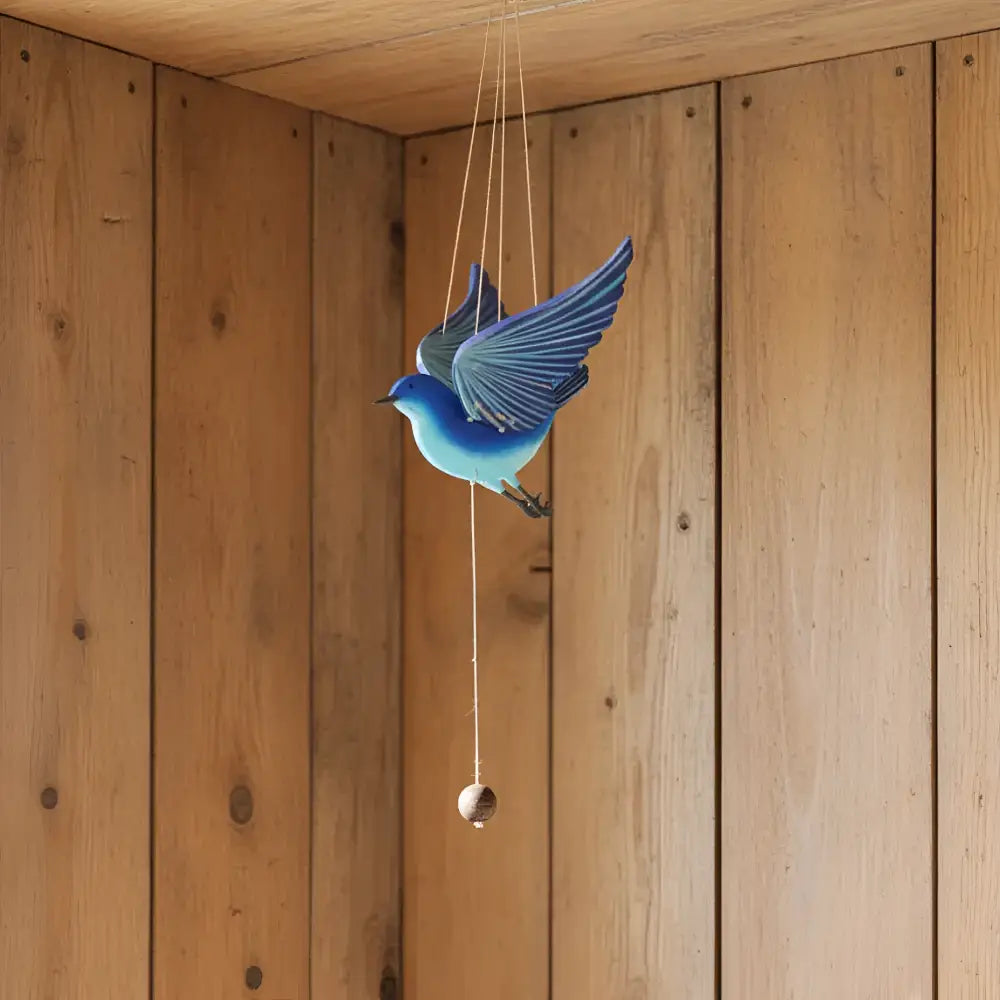 Handcrafted blue bird flying mobile with detailed wing feathers and a hanging wooden bead for happiness creates ethical decor