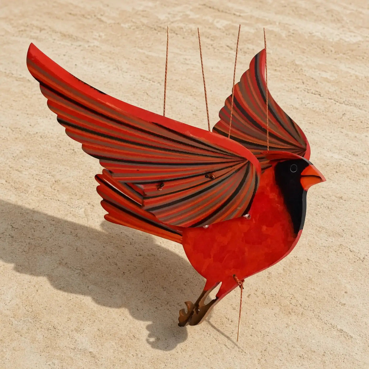 A handcrafted cardinal mobile made of painted metal featuring a vibrant red bird with black accents and playful flutter wings perfectly balanced