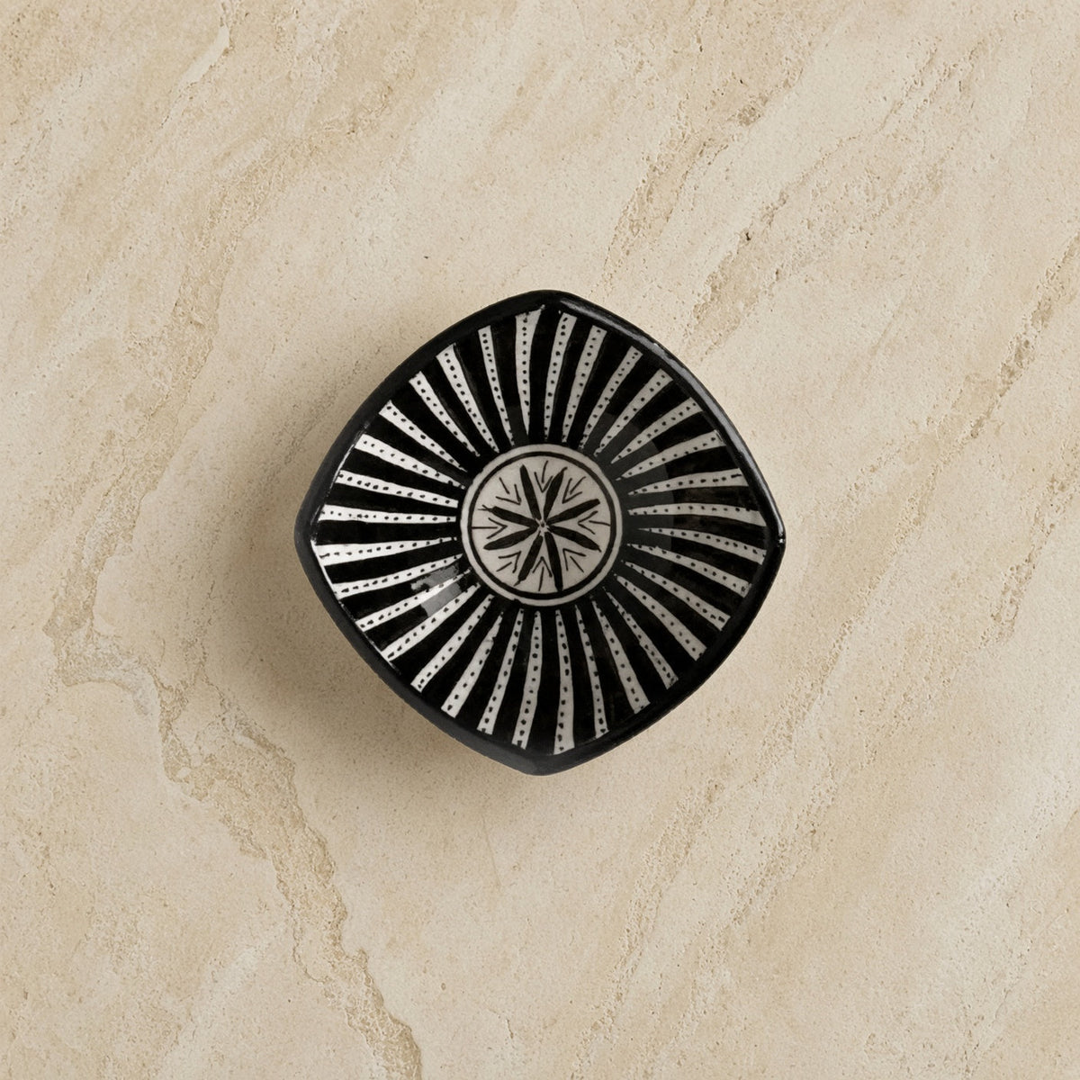 Black handcrafted ceramic bowl from safi morocco with white sunburst star pattern inspired by rugged atlantic design