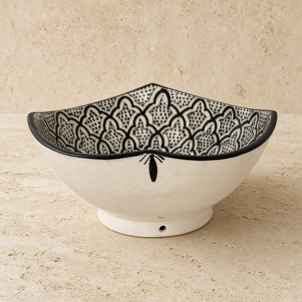 White handcrafted ceramic bowl from safi morocco with black geometric and floral patterns and rugged atlantic vibe