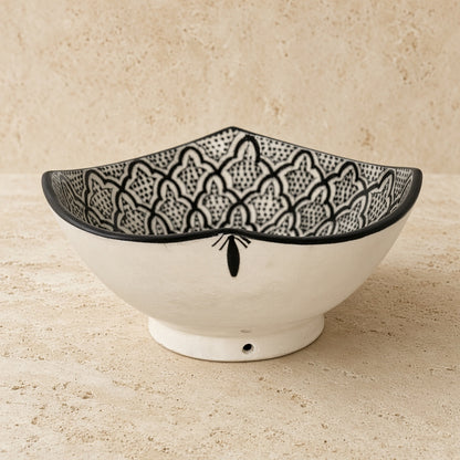 White handcrafted ceramic bowl from safi morocco with black geometric and floral patterns and rugged atlantic vibe
