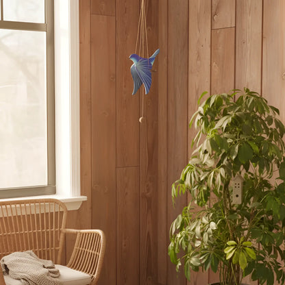 A handcrafted blue bird flying mobile features a blue bird wind chime with a metallic finish hanging on a wooden wall