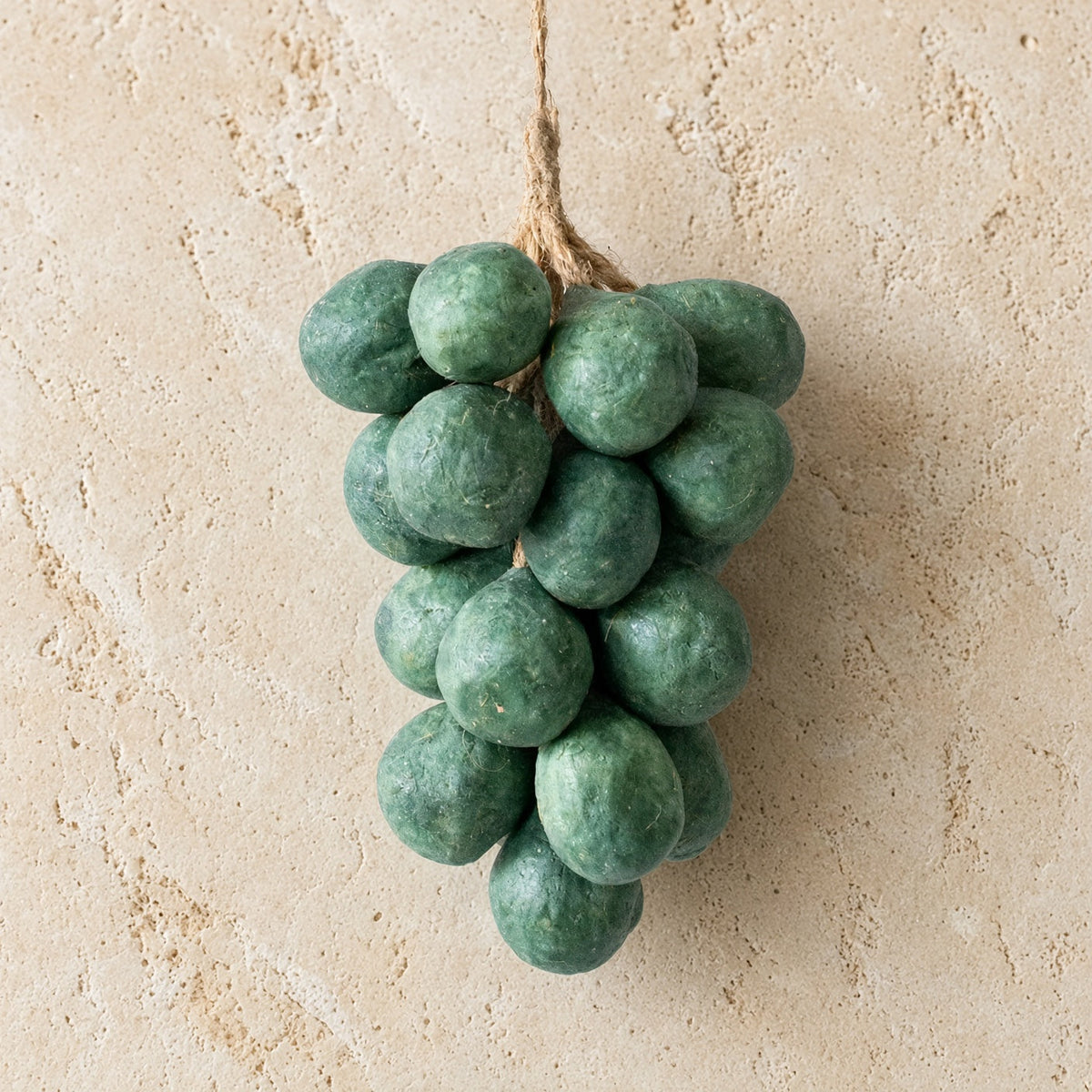 A cluster of green handcrafted grape soap ornaments made with olive oil hanging from rustic twine