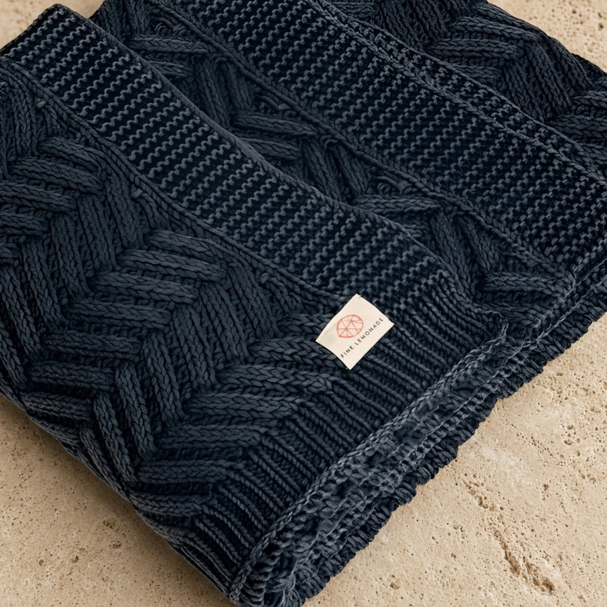 Handcrafted navy blue chevron cable knit scarf with tactile luxury and artisanal craftsmanship in textured pattern