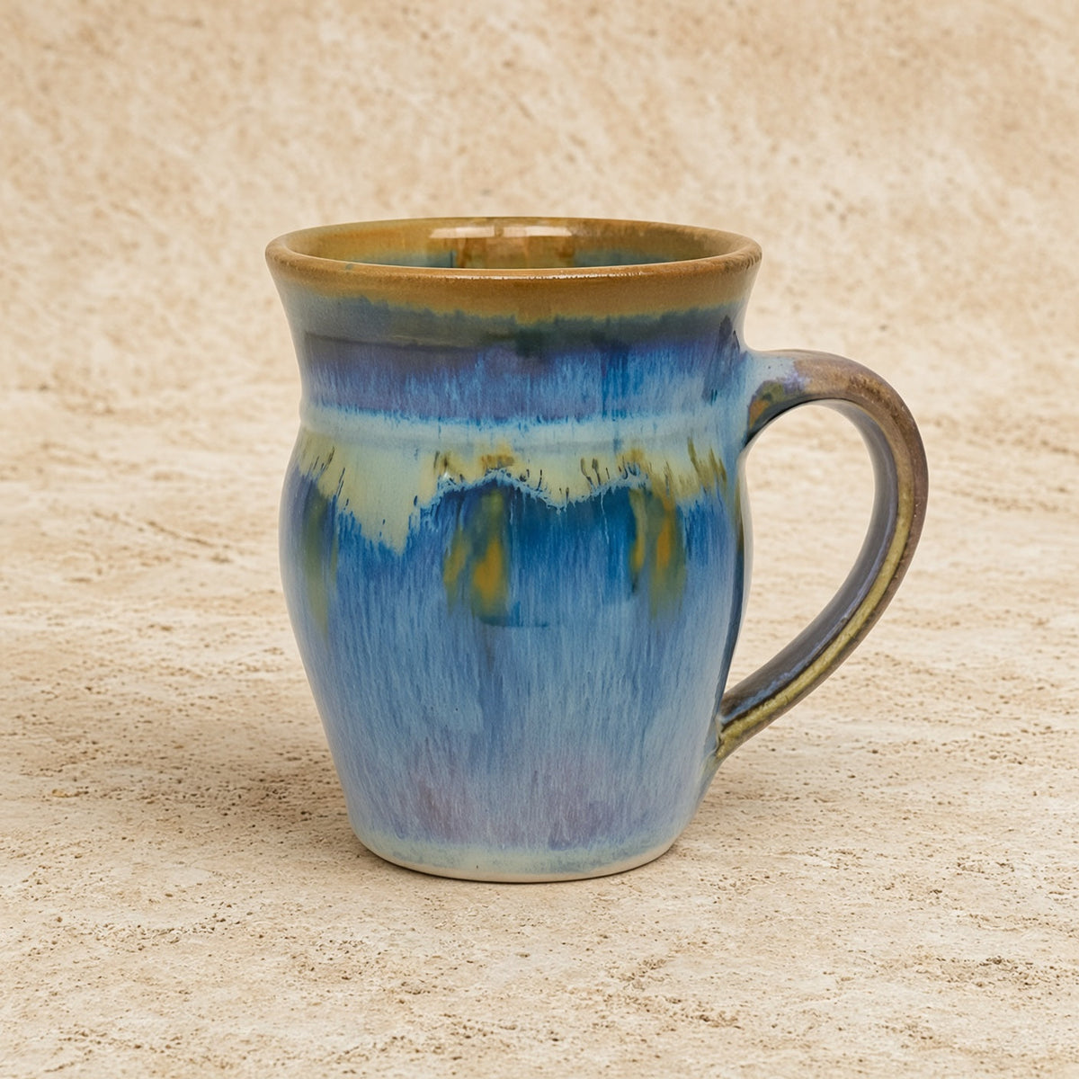 Handcrafted pottery mug with glaze dances in blue bronze green and gold perfect for cozy sipping