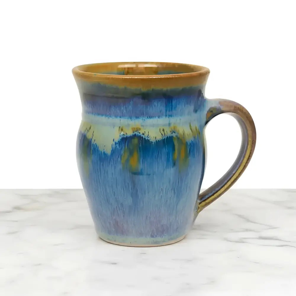 Handcrafted pottery mug with reactive glaze dances in blues bronze and purple evoking northern light vibes