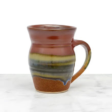 Handcrafted pottery mug with glossy earthy glaze in browns blue and green featuring aztec sunrise vibes