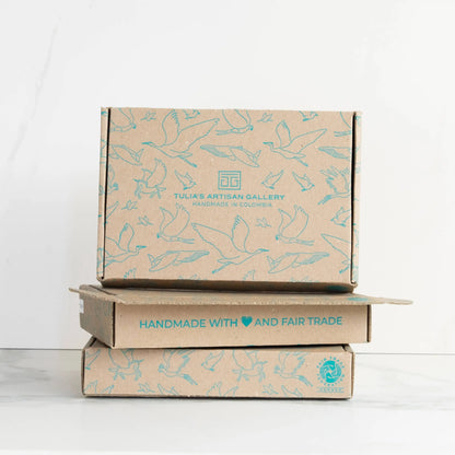 Stack of three brown cardboard boxes with light blue bird art from tulia’s artisan gallery woman-owned eco-friendly handmade