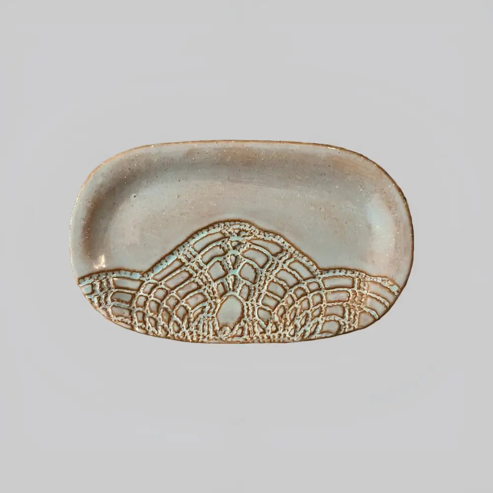 Handcrafted stoneware dish with textured mountain design in earthy tones