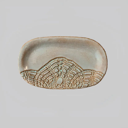 Handcrafted stoneware dish with textured mountain design in earthy tones