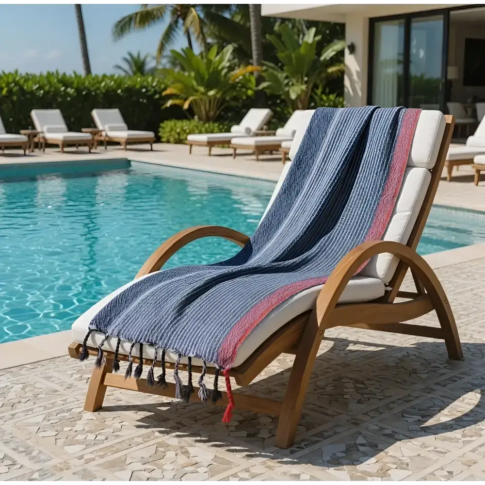 Blue and pink striped handmade hand towel in turkish cotton draped over wooden lounge chair with tassels indigo tribeca