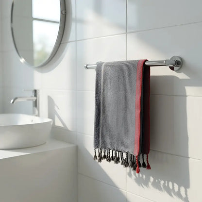 Gray and red striped handmade turkish cotton hand towel with tassels hanging on chrome towel rack indigo tribeca