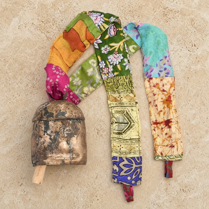Handmade copper bell with rustic wooden handle and colorful upcycled sari fabric ribbon featuring vibrant patterns