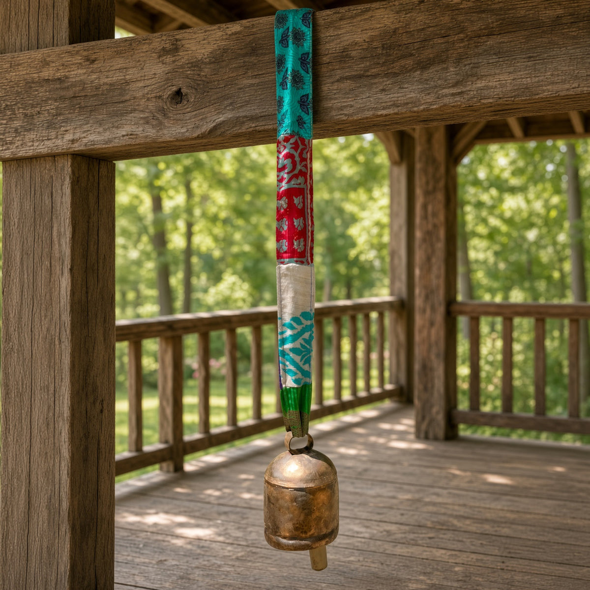 Handmade copper bell with colorful upcycled sari fabric hanging from wooden beam with sari ribbon bell strap