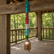 Handmade copper bell with colorful upcycled sari fabric hanging from wooden beam with sari ribbon bell strap