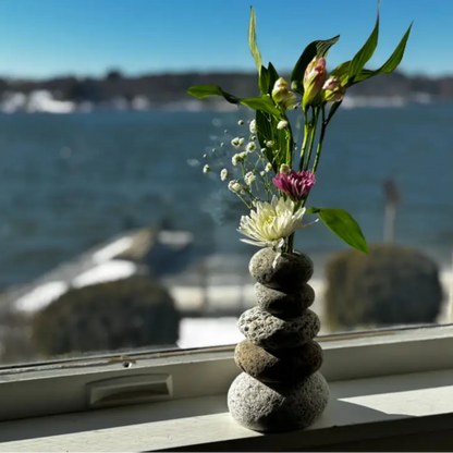 Handmade eco-friendly cairn vase with purple and white flowers and green leaves