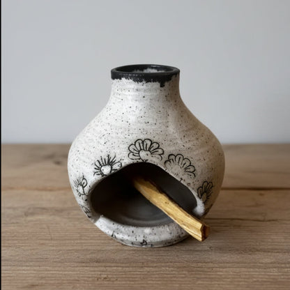Handmade ceramic incense burner with black floral design holding palo santo wood eco-friendly vibe
