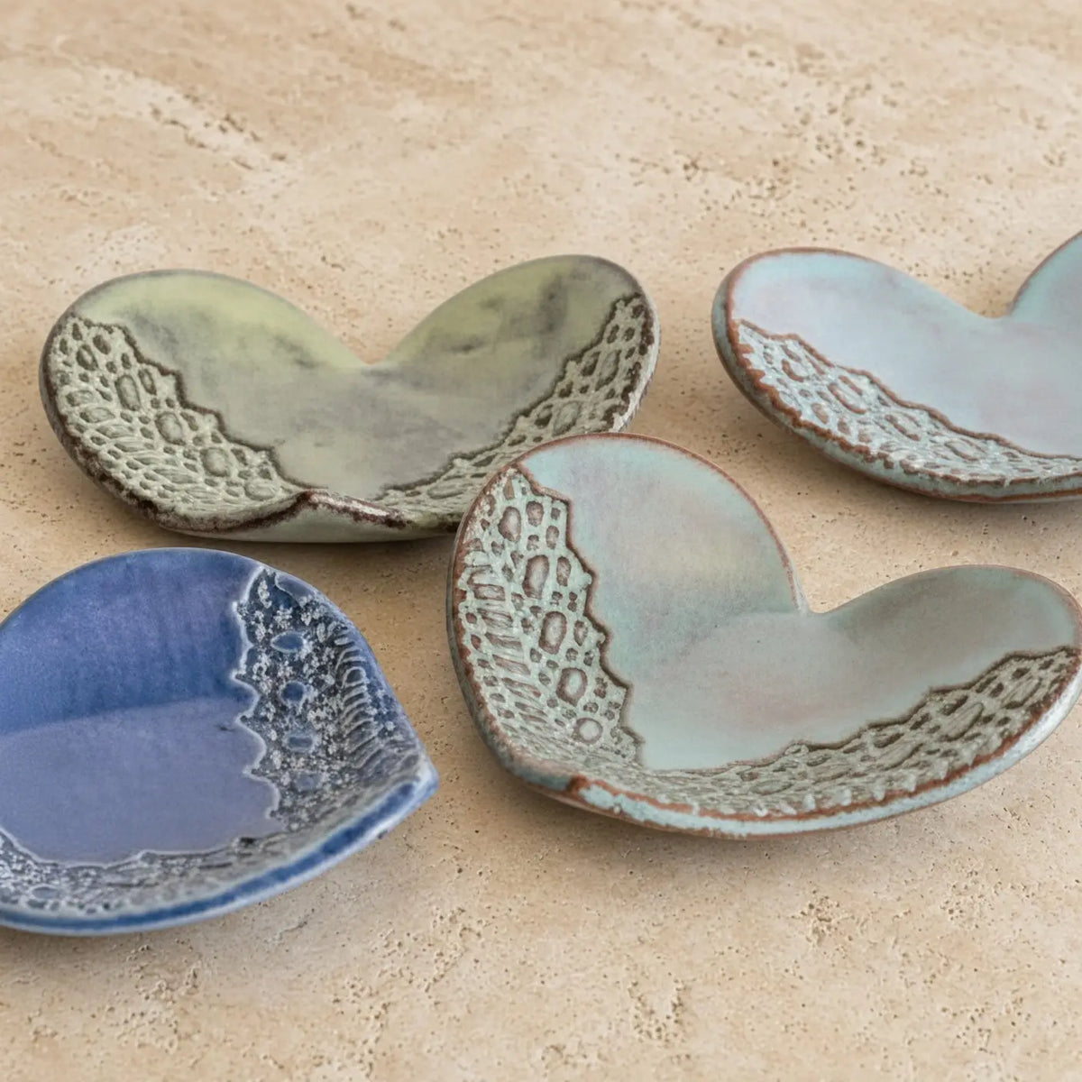 Handmade ceramic heart trinket dish with textured lace edge glazed in soft blue and muted green tones for rings