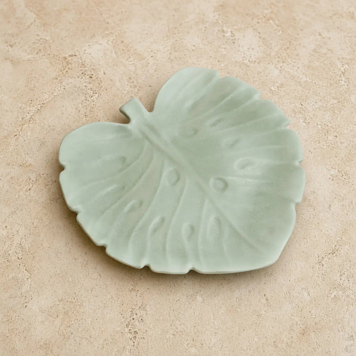 Handmade concrete monstera leaf dish in delicate mint green with raised veins perfect for corralling soap