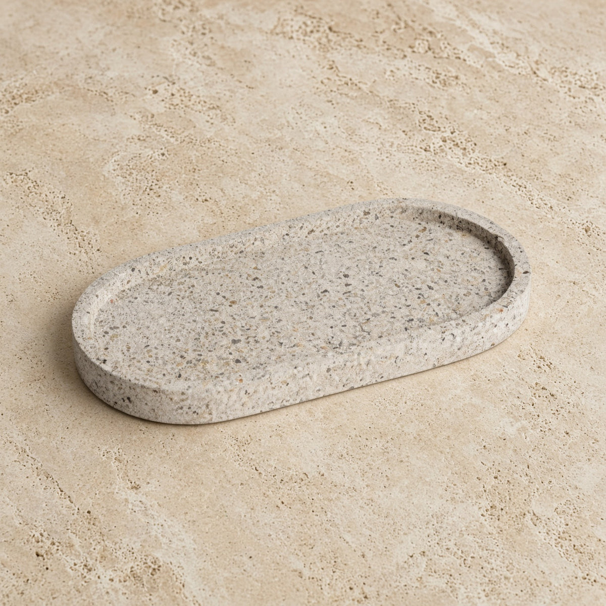 A handmade concrete small narrow tray with a sleek oval shape and speckled gray surface perfect as a jewelry organizer