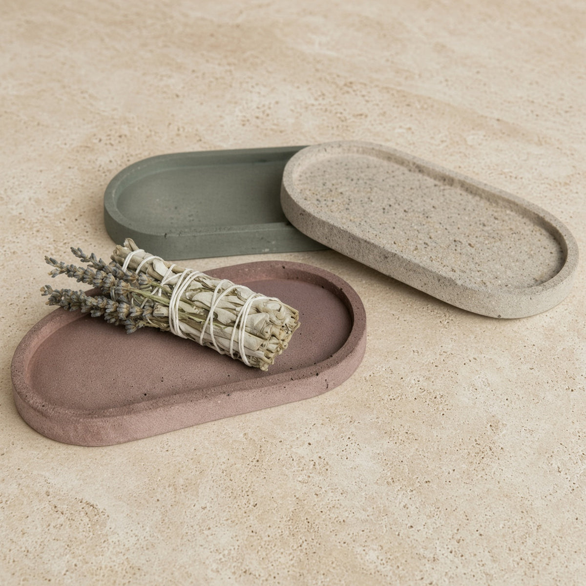 Handmade concrete small narrow trays in muted earth tones with one used as a coordinating sage holder or jewelry organizer