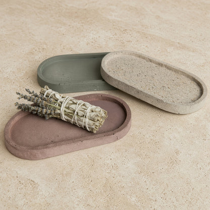 Handmade concrete small narrow trays in muted earth tones with one used as a coordinating sage holder or jewelry organizer