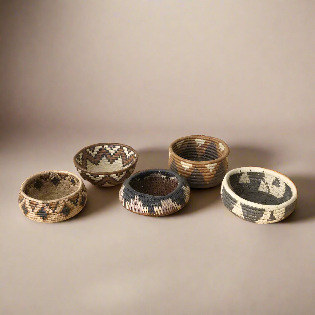 Five colorful South African woven baskets with geometric patterns in a woven basket set