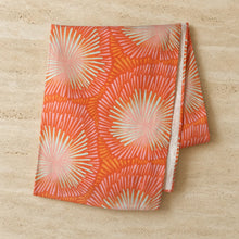 A handmade european linen table runner with a lively coral sunburst design featuring a coral burst pattern
