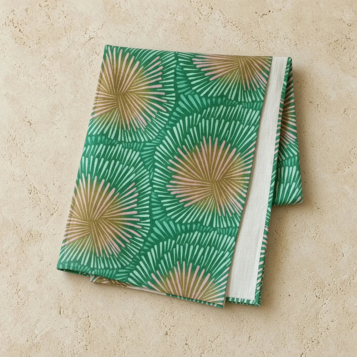 Folded handmade european linen table runner with green burst pattern and fan-like design in green and beige colors