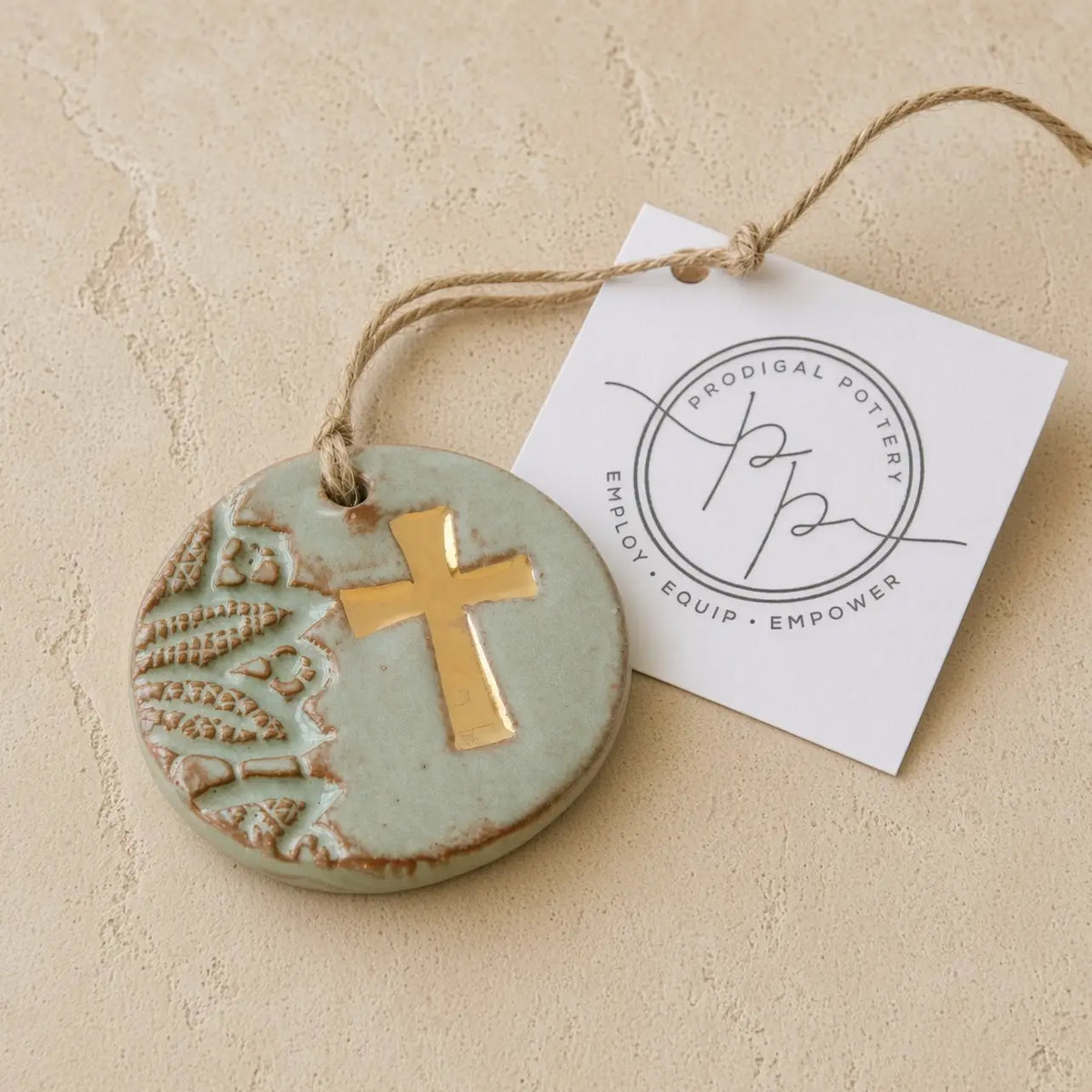 Handmade gold leaf cross ornament in matte sage green ceramic with embossed leaves supports women rebuilding