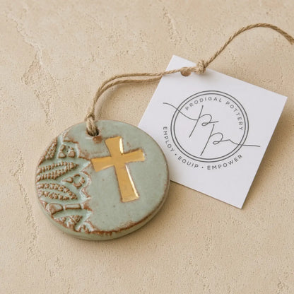Handmade gold leaf cross ornament in matte sage green ceramic with embossed leaves supports women rebuilding