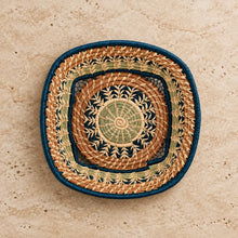 Handwoven guatemalan basket with colorful concentric circles in tan sage green and deep teal strands and blue rim