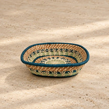 Handmade guatemalan basket with natural tan base and colorful teal and light green woven patterns in an oval shape