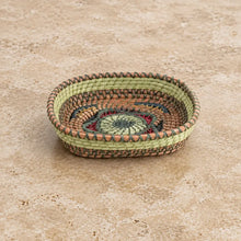 Handmade guatemalan small basket with a handwoven oval shape and vibrant green red and brown spiral floral design