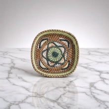 Handmade guatemalan small basket with a handwoven spiral pattern in earthy brown green and cream tones