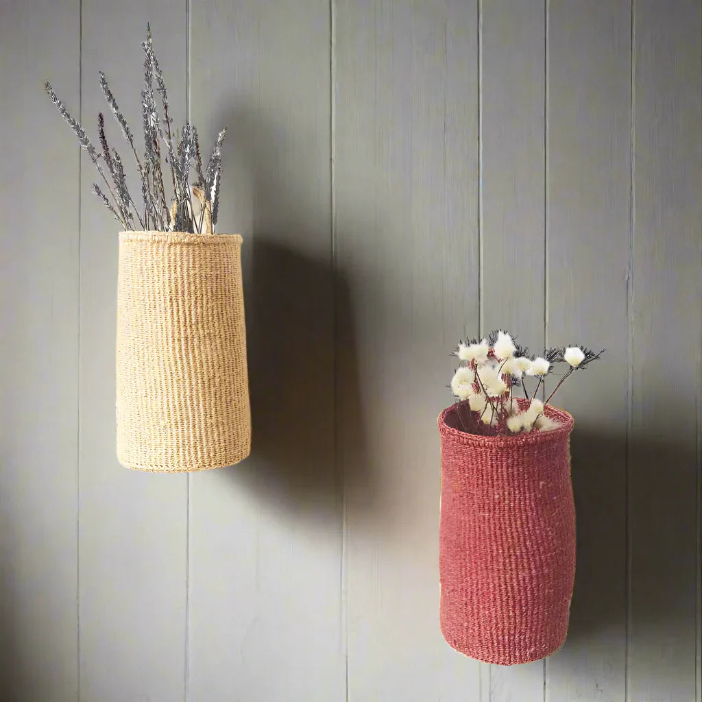 Two woven hanging sisal baskets, one beige with lavender, one reddish-pink with cotton sprigs