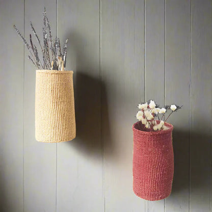 Two woven hanging sisal baskets, one beige with lavender, one reddish-pink with cotton sprigs
