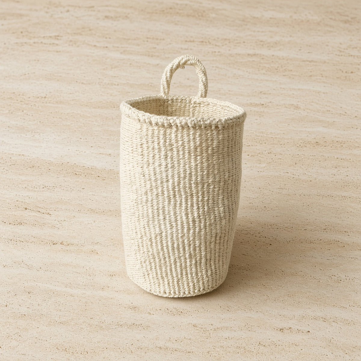 Cream-colored handmade hanging sisal basket with sturdy loop handle for easy hanging and storage
