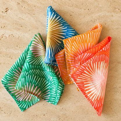 Set of four handmade european linen napkins with bright colors set featuring bold sunburst patterns in green and orange gradients