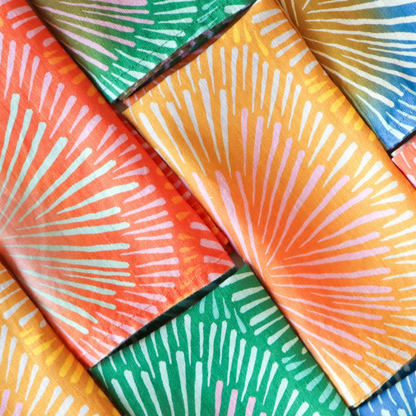 Handmade european linen napkins in bright colors set with vibrant orange and green sunburst pattern for lively table decor