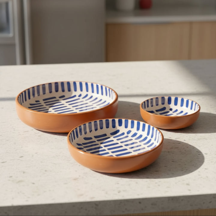 Three handmade nested Moroccan ceramic bowls with blue dashed pattern and terracotta exteriors