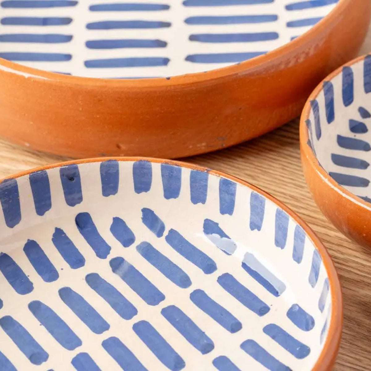 Three handmade nested Moroccan ceramic bowls with blue and white striped patterns